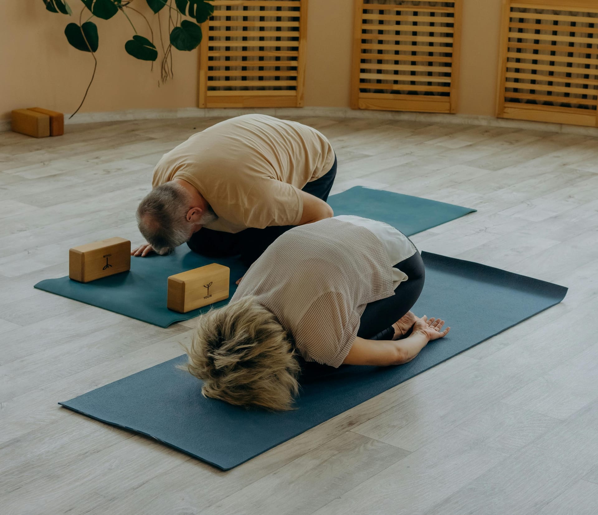 Two people practicing Child's Pose with blocks